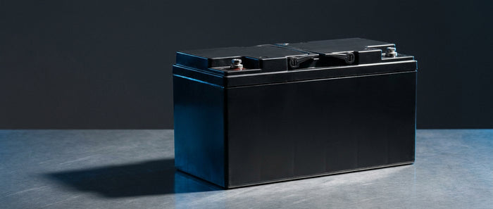 A sealed VRLA AGM battery photographed in professional studio lighting against a dark charcoal background, conveying industrial reliability and technical precision.